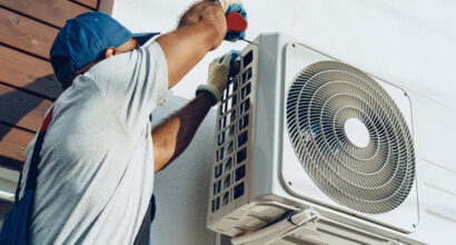 Repairman in uniform installing the outside unit of air conditioner close up